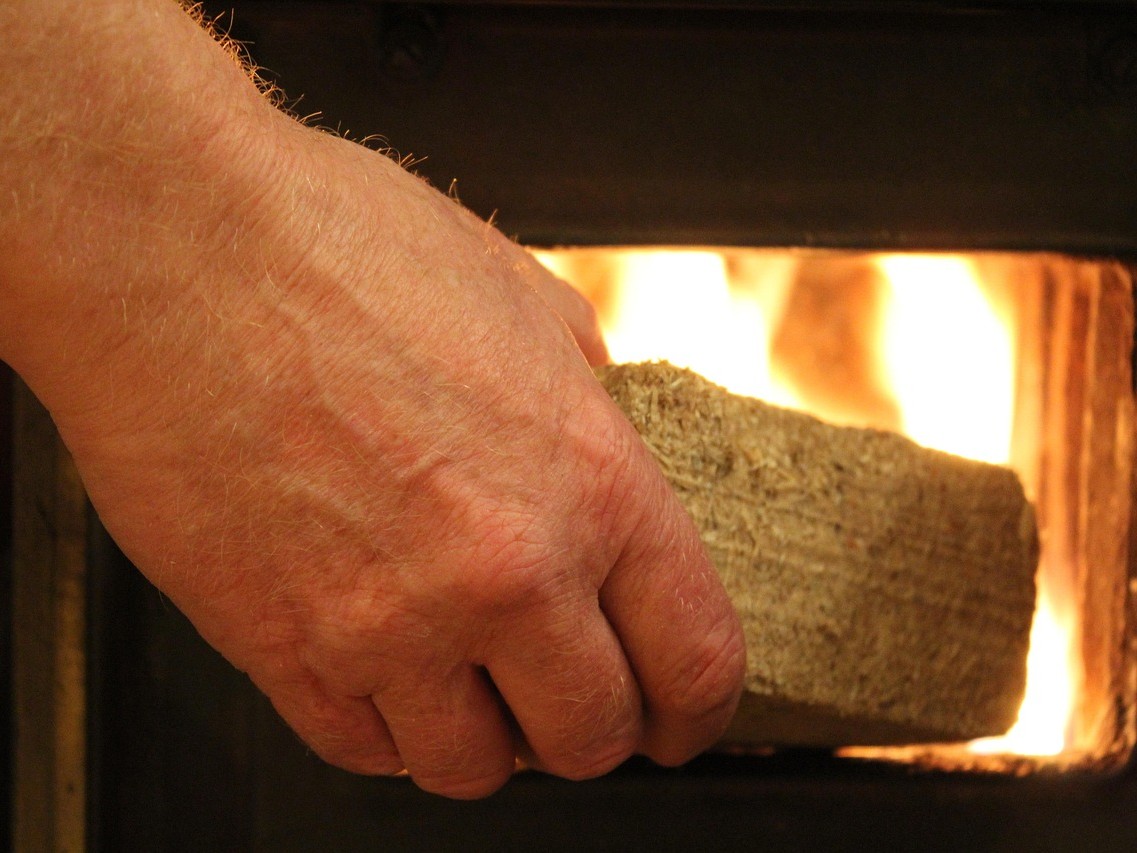 Brikett wird in einem Kamin gegeben